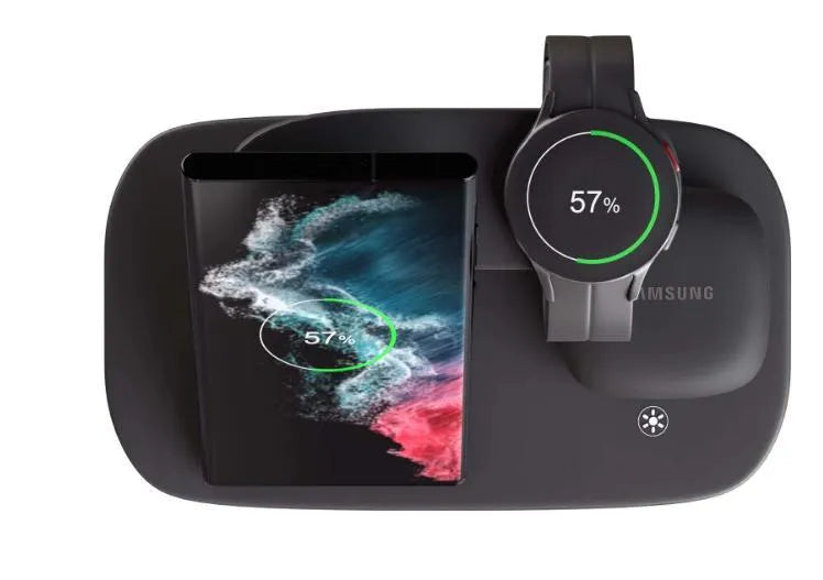 A vertical 3-in-1 wireless charging stand holding a mobile phone, a smartwatch, and headphones on a desk.