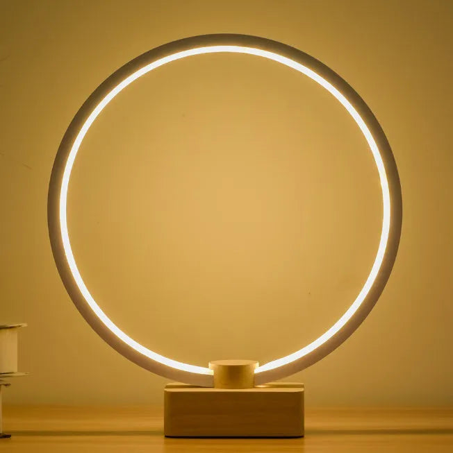 Round small solid wood and bamboo USB-powered LED night lamp on a table.