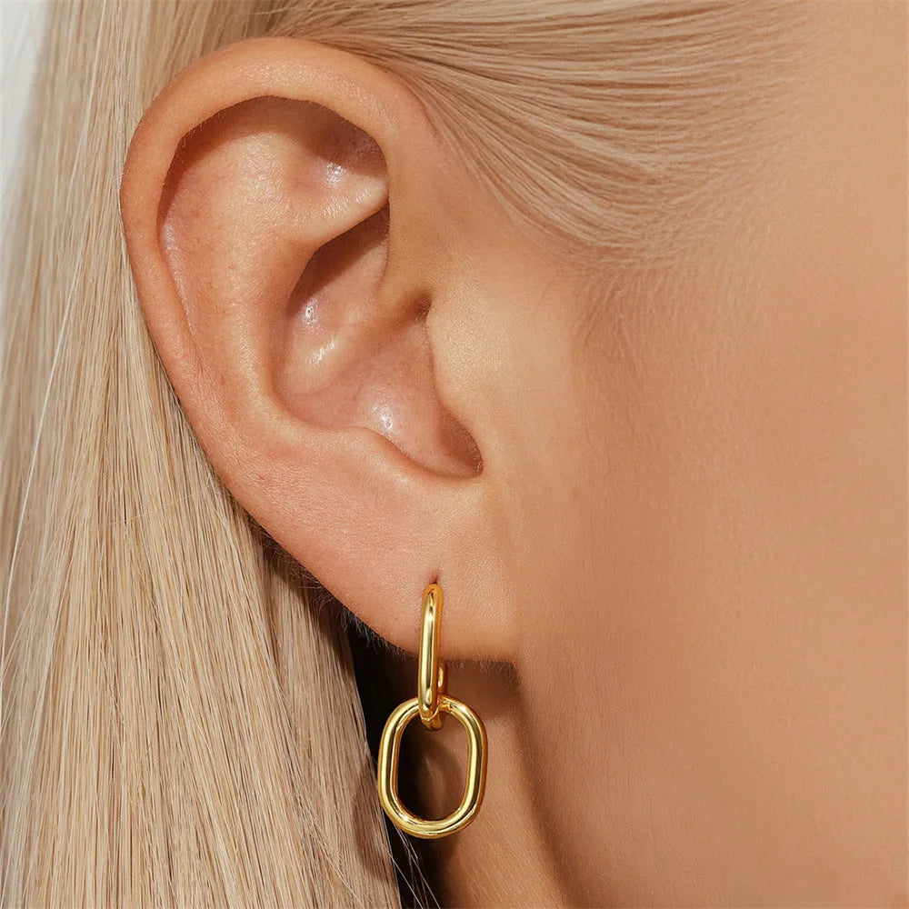 A pair of geometric brass earclip earrings with round diamond details on a gold electroplated copper base.