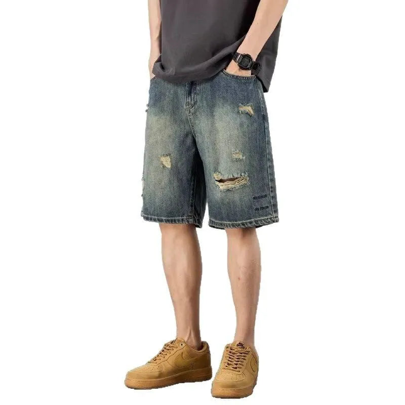 Man wearing blue retro loose hole distressed denim shorts with a straight leg cut