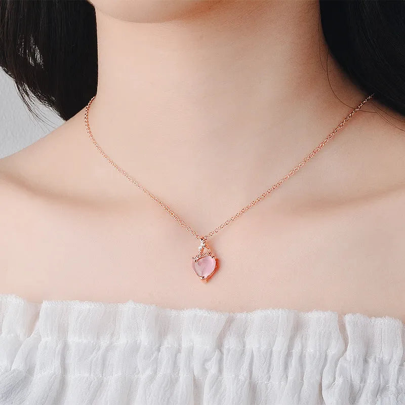 Women's pink heart crystal pendant necklace with rose gold chain on white background