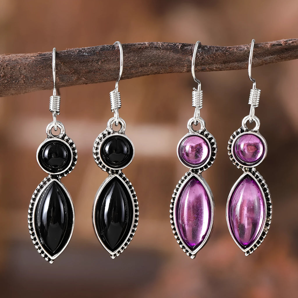 Close-up of geometric vintage pendant earrings in black and purple with a metallic shine.