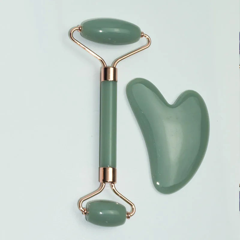 Stainless steel facial massage roller and heart-shaped gua sha scraping plate on a simple background.