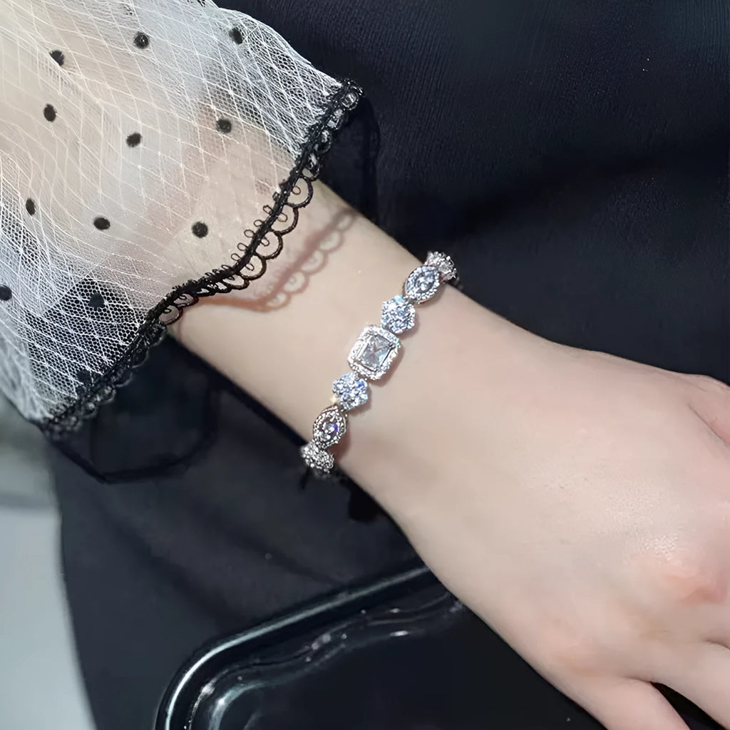 Women's geometric silver bracelet with inlaid white zircon stones on a wrist, showing adjustable clasp.