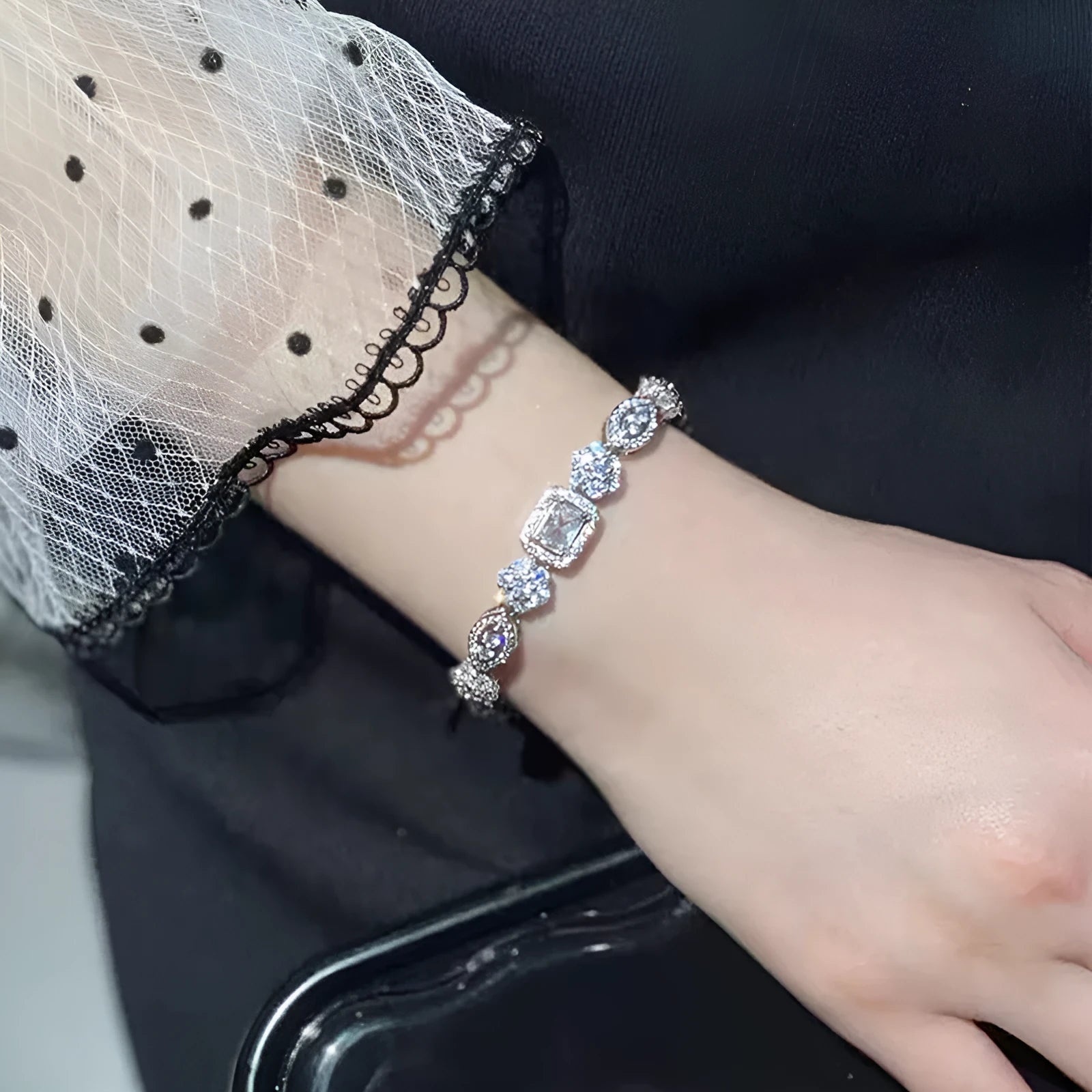 Women's geometric silver bracelet with inlaid white zircon stones on a wrist, showing adjustable clasp.