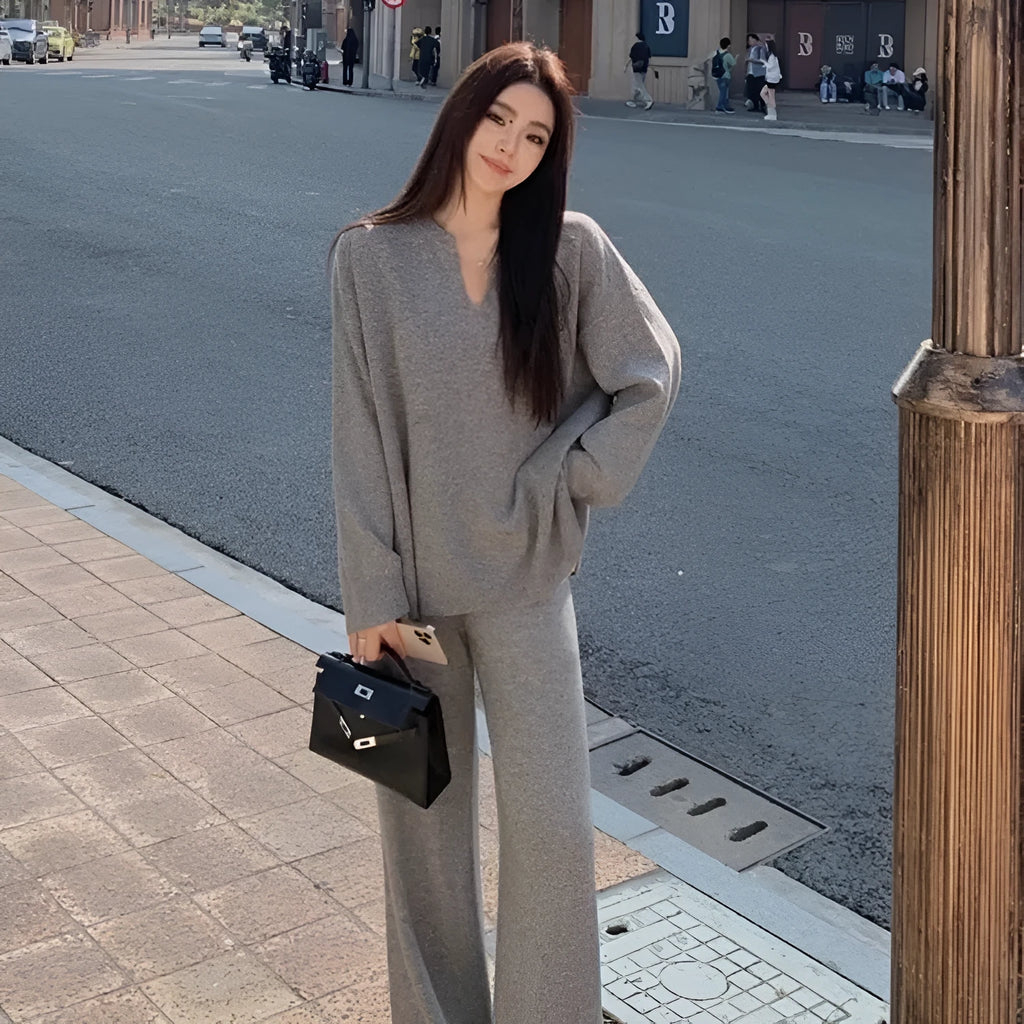 Women's V-neck knitted two-piece suit with wide-leg pants in beige, showing asymmetric pleating on top