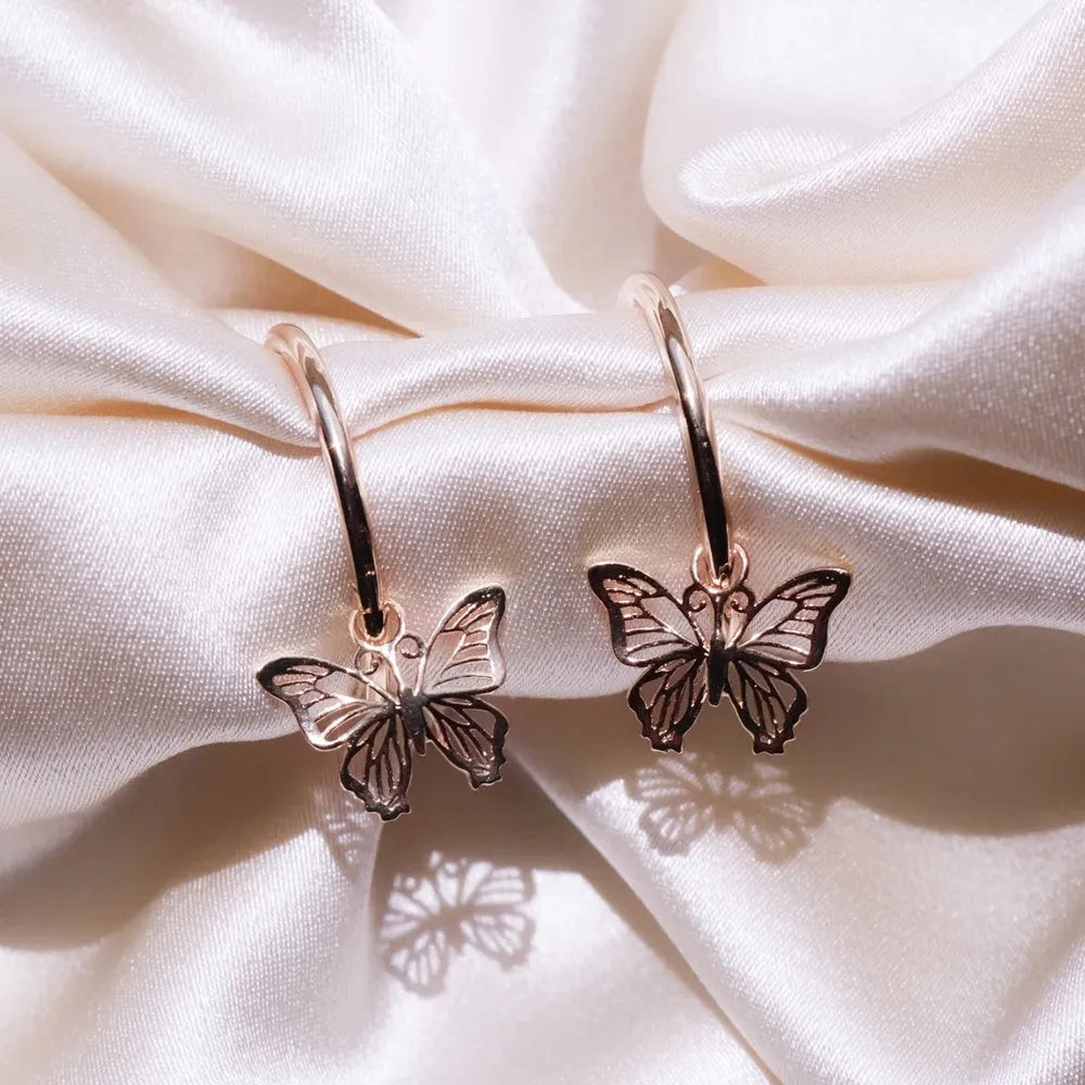 Gold copper alloy stud earrings with butterfly and bow design on white background