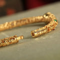 Retro-style open copper bracelet with a detailed gourd charm on a wrist.