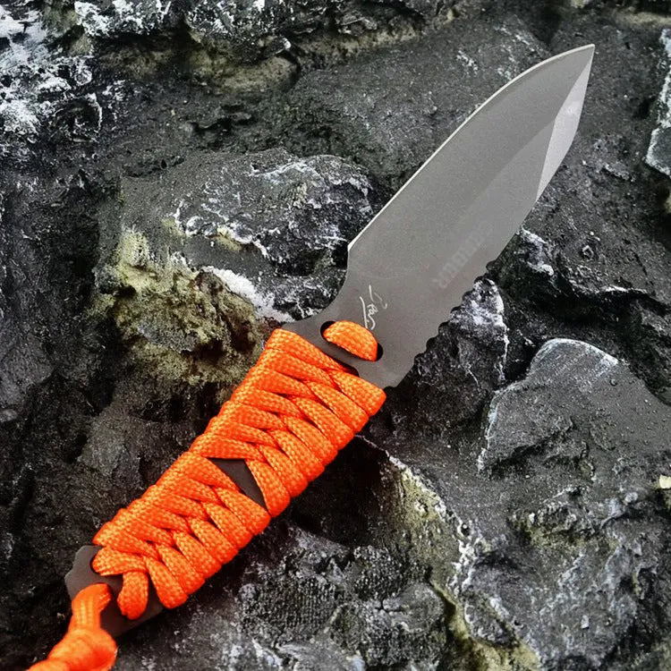 Straight camping survival knife with binding rope handle next to ABS sheath