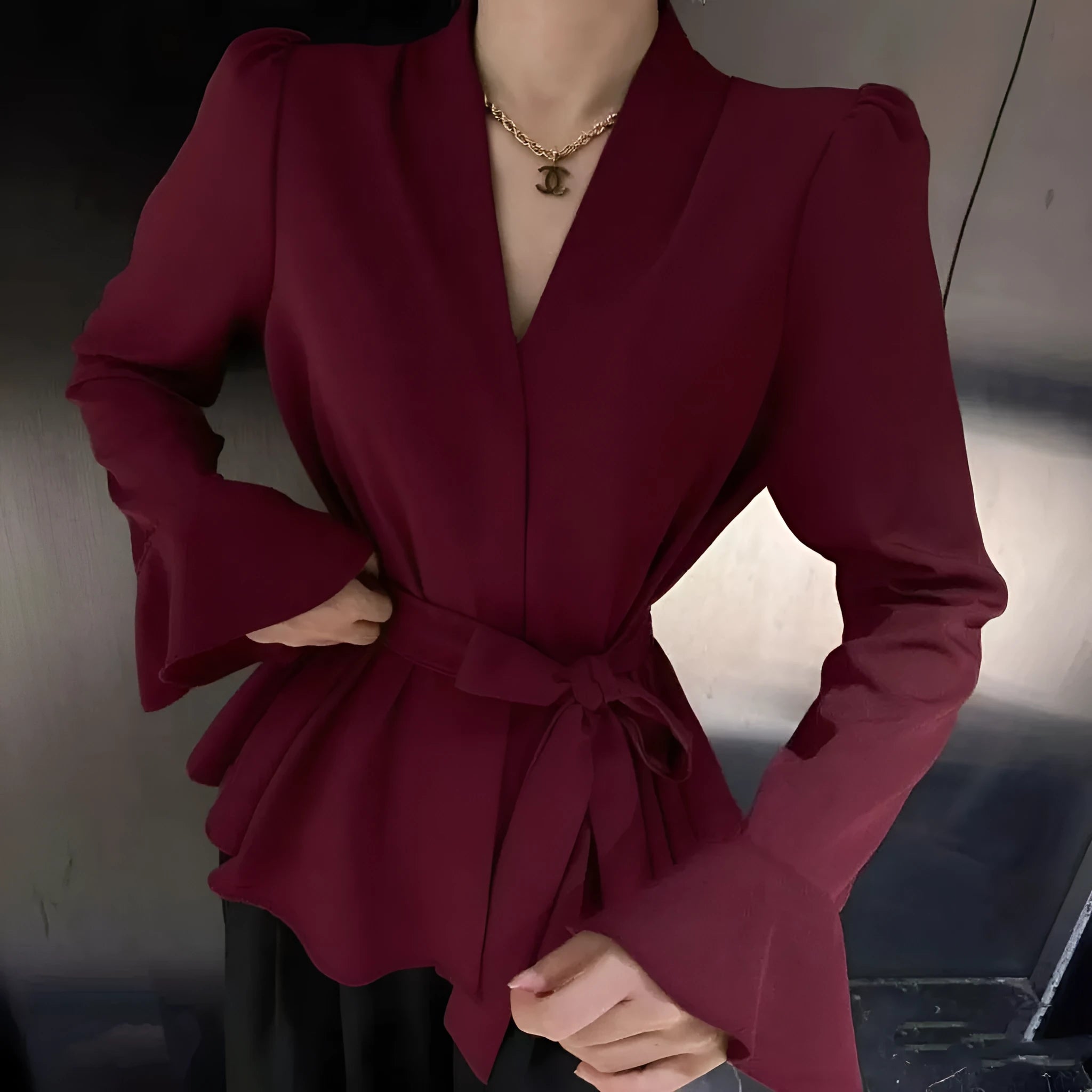 Woman wearing a black tied shirt with a French-style collar and long bell sleeves.