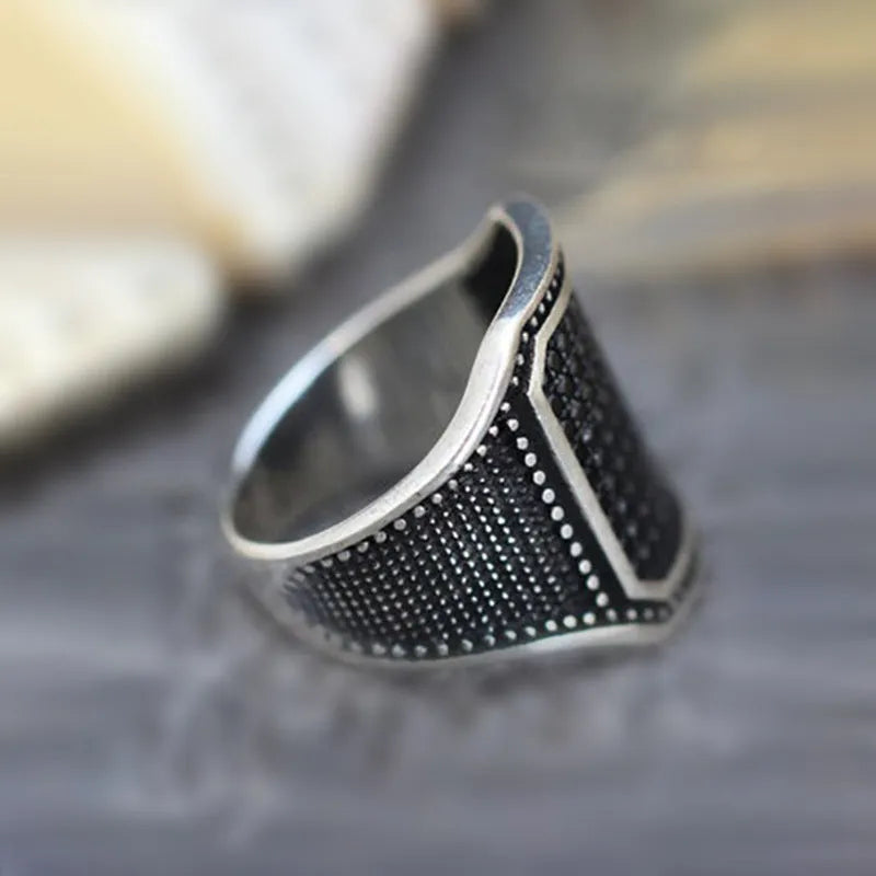 Black alloy ring with copper inlay details and a central sparkling zircon stone on a plain background.