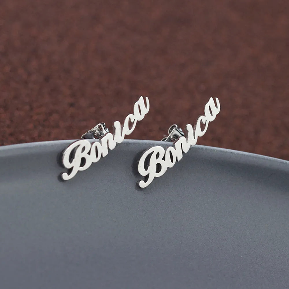 Custom English letter name earrings in rose golden finish on a plain background
