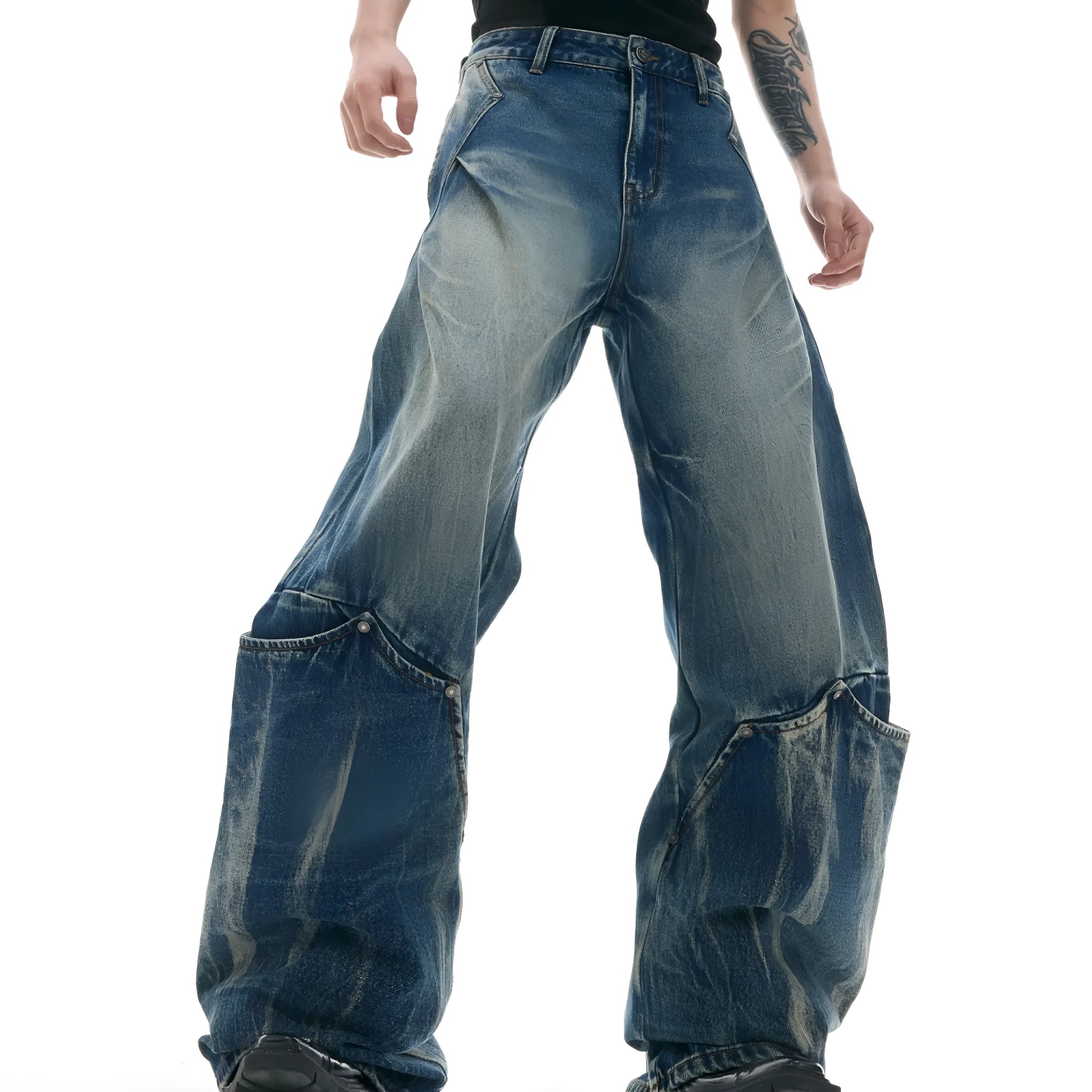 Man wearing verdant blue loose-fit retro jeans with a distinctive white burst pattern wash and a curved knife leg cut.