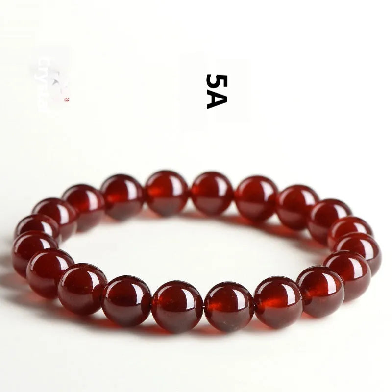 Natural orange red garnet ball bracelet with a central Ruyi knot charm on a white background.