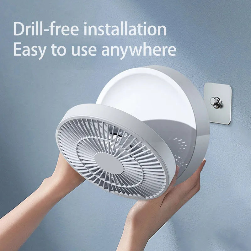 White portable folding electric fan with remote control and warm night light on a desk.