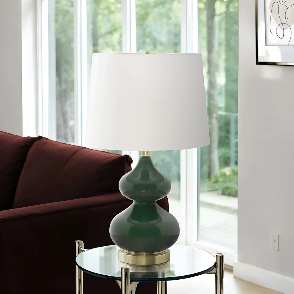 Blue cloth shade desk lamp with a clear crystal glass base on a wooden desk.