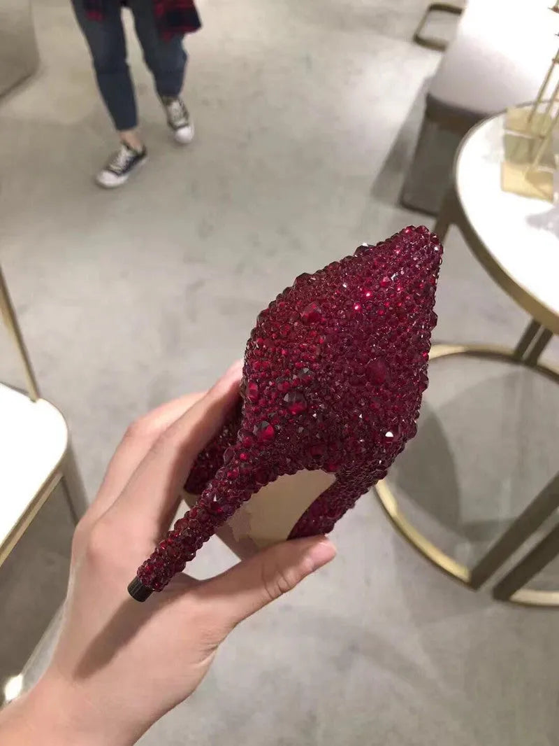 Gold women's pointed toe high heels with rhinestone and sequin decoration on a stiletto heel.