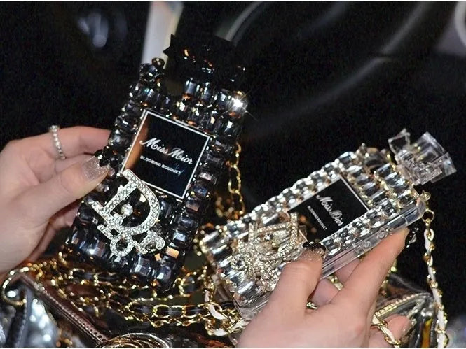 Perfume bottle and bow design iPhone case with metal chain, in matte black TPU, shown fitted on an iPhone.