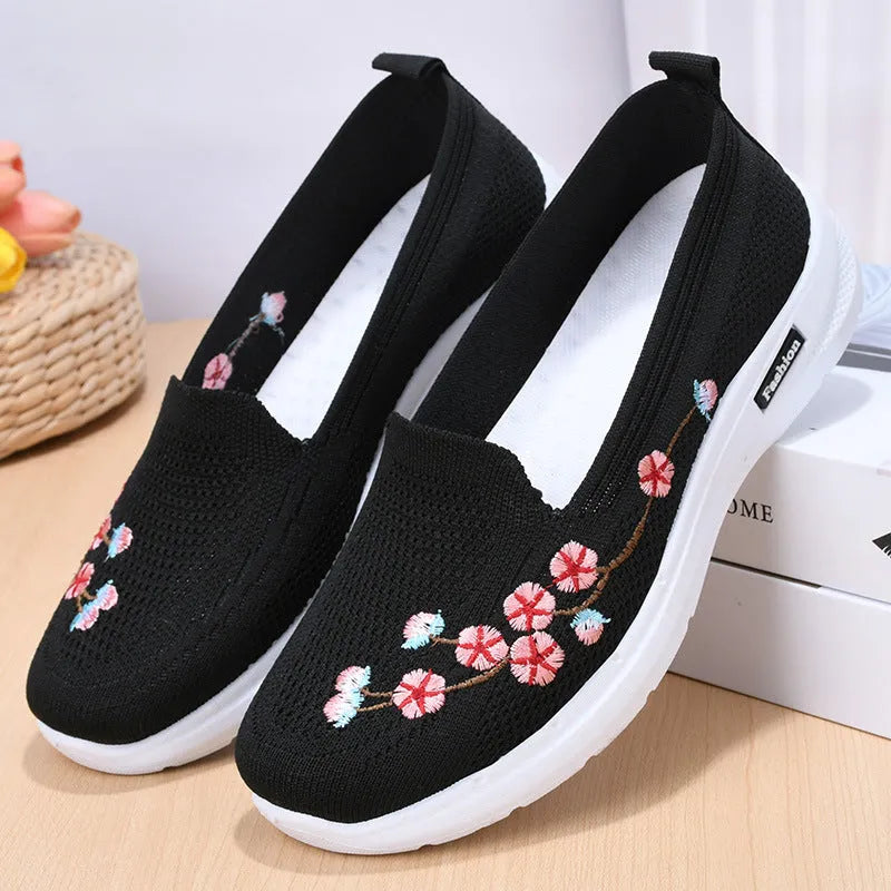 Women's embroidered floral flat pump in woven fabric with a low heel and round toe.