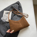 Retro suede underarm bag in black with bucket shape, sandwich pocket, and visible sewing detail
