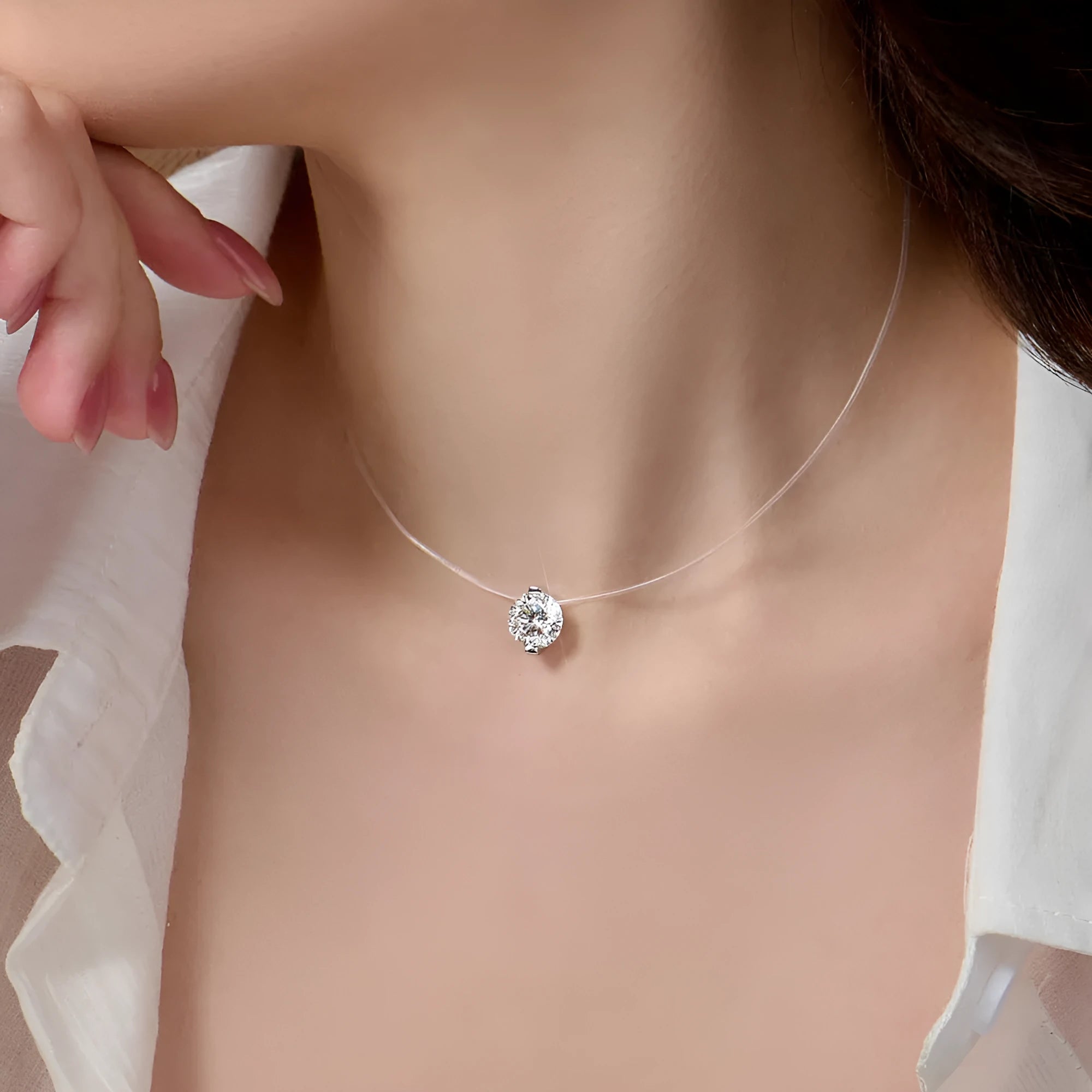 Close-up of a women's sterling silver plum blossom pendant with a blue green moissanite on an invisible fishing line necklace.