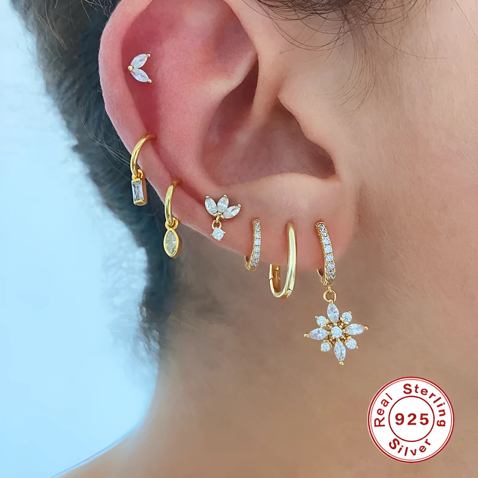 A pair of sterling silver snowflake pendant earrings with a gemstone, shown in yellow gold and white gold colour finishes.