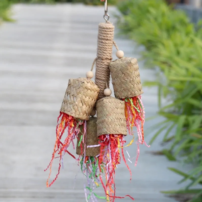 A parrot toy made of wood and sisal rope with colourful shredded paper attachments.