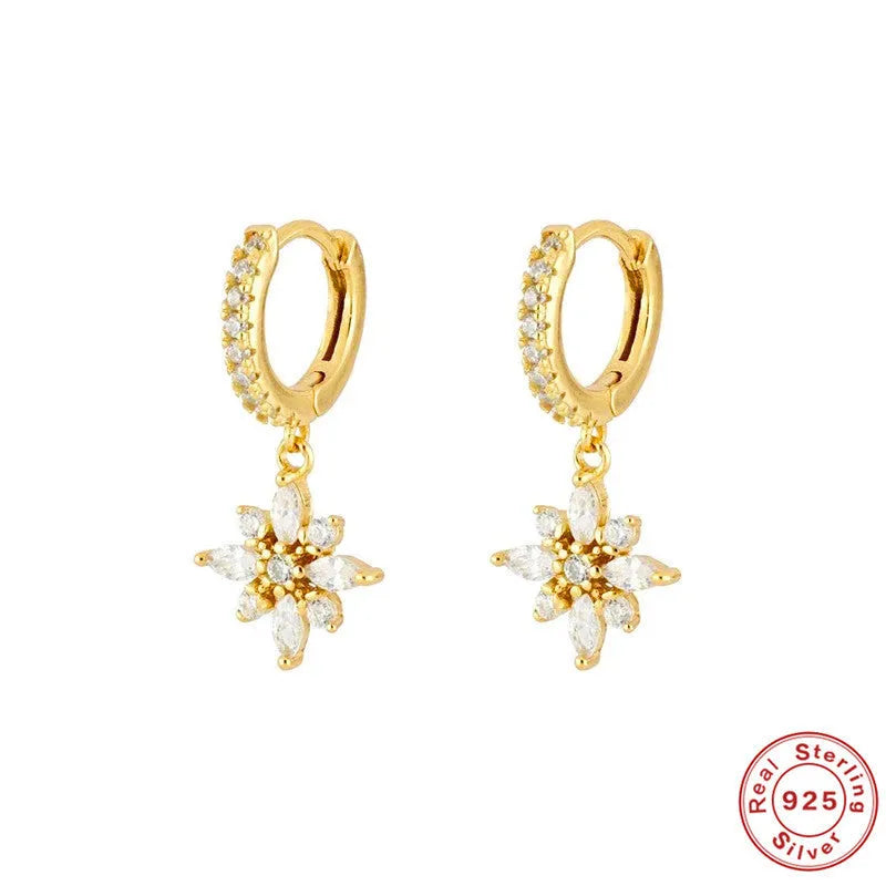 A pair of sterling silver snowflake pendant earrings with a gemstone, shown in yellow gold and white gold colour finishes.