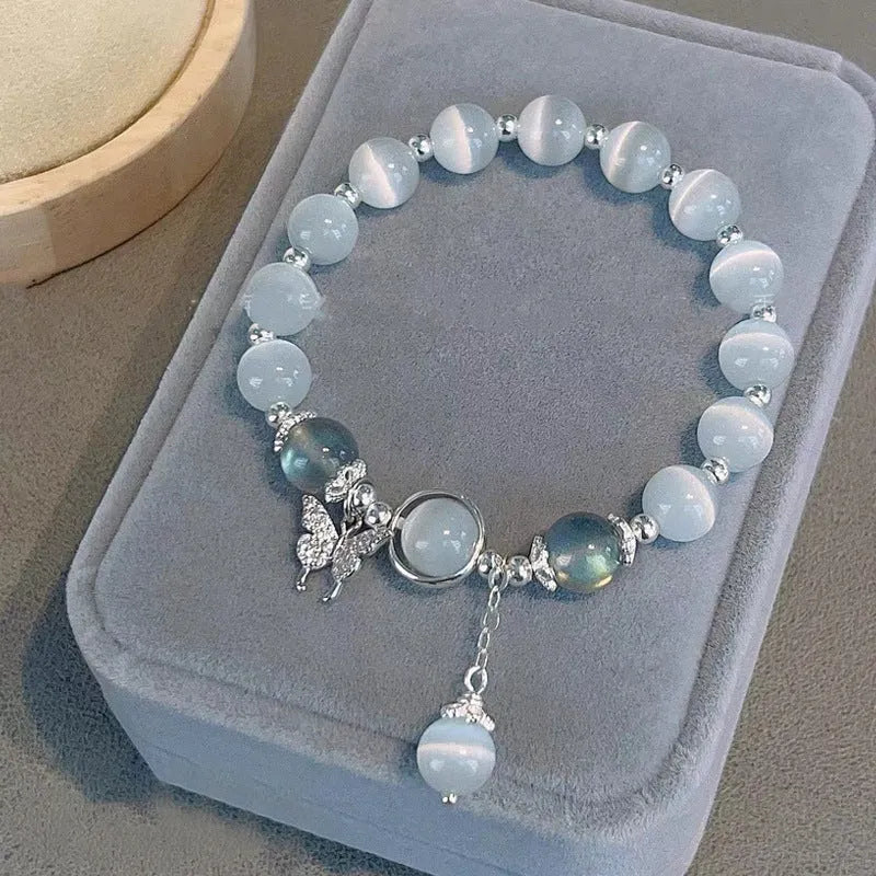 Close-up of a women's opal cat's eye stone beaded bracelet with diamond-shaped beads on a wrist.