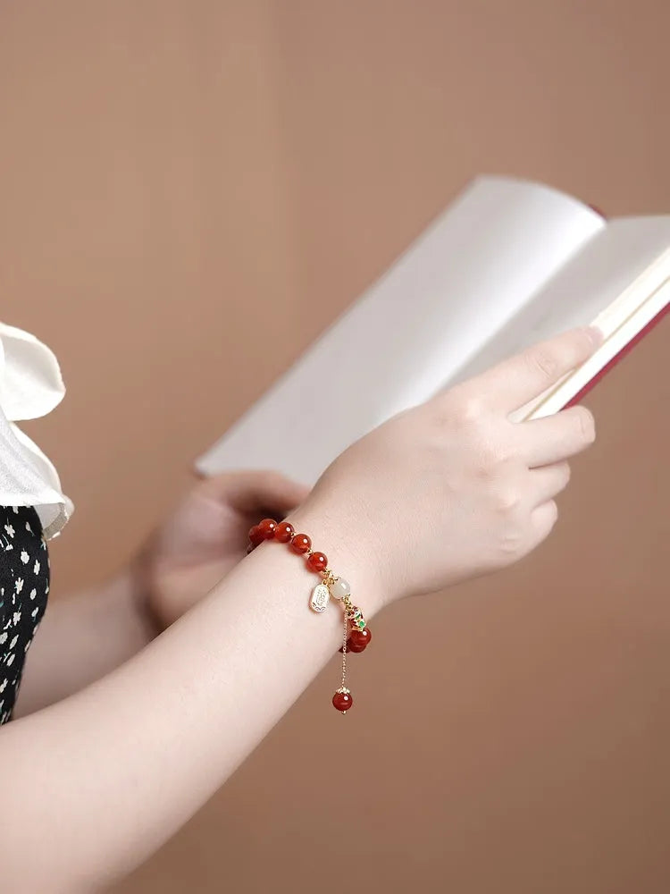 Gold-plated women's bracelet with red agate and Hetian jade beads in a traditional pattern.