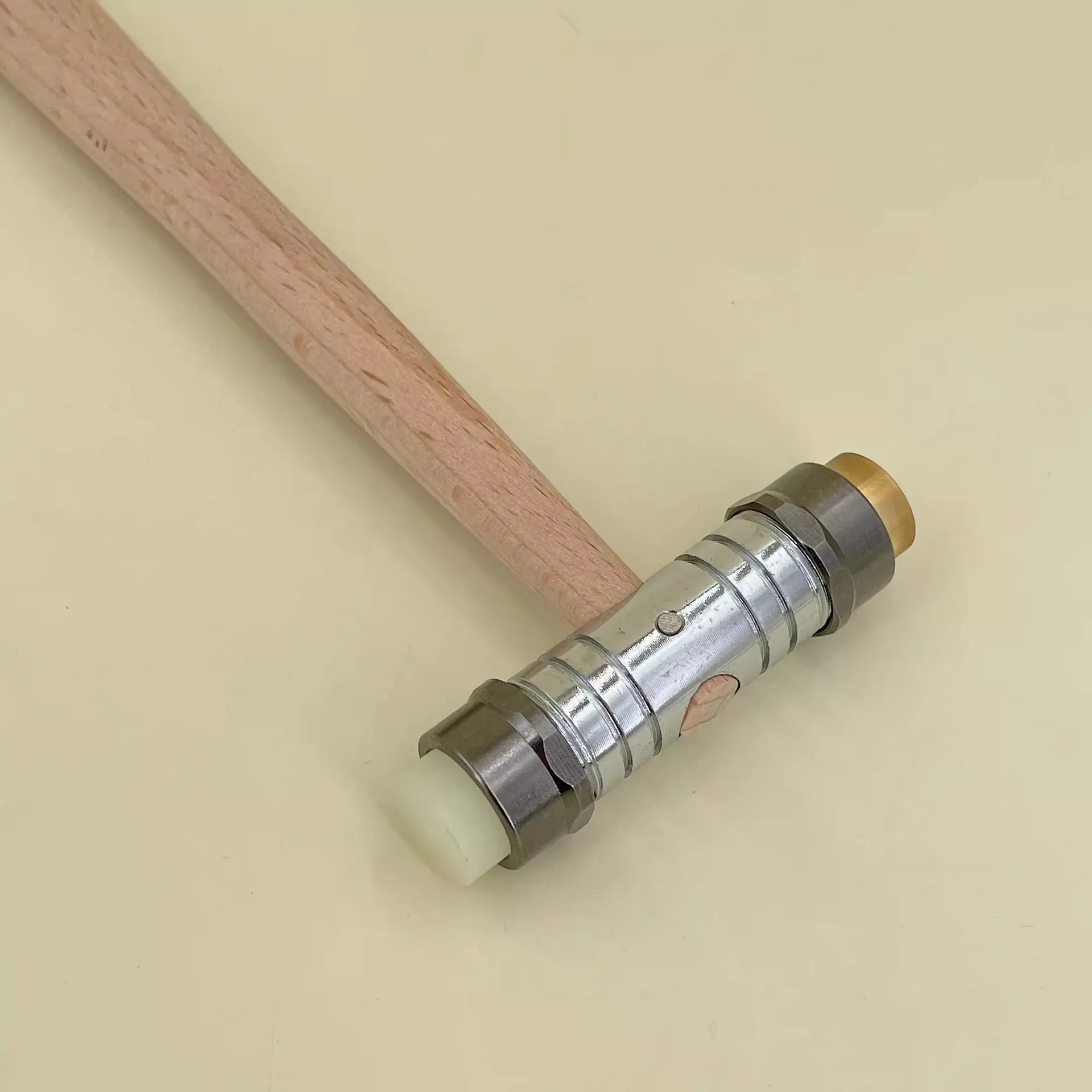 Brass watch repair hammer with wooden handle on a workbench