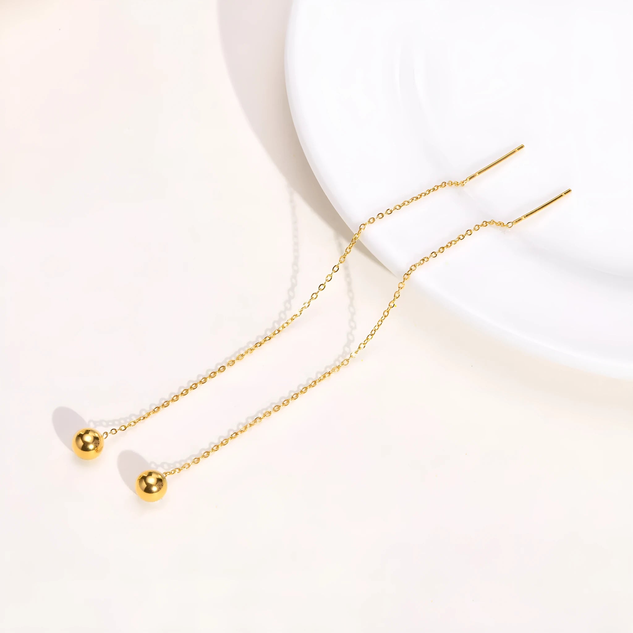 Gold-toned alloy drop earrings with round bead design on white background