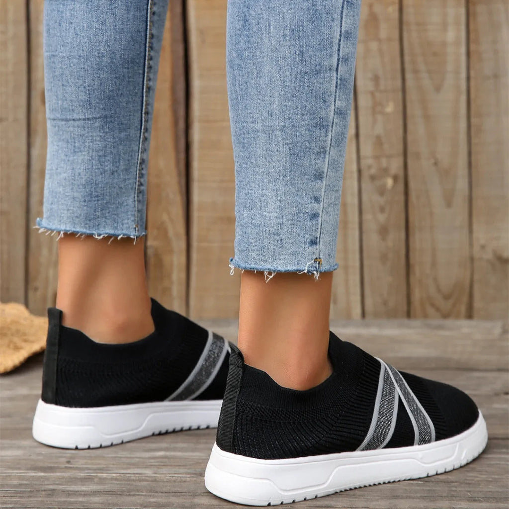 Black women's low-top flyknit mesh flat shoes with round toe and tassel detail on a rubber sole.