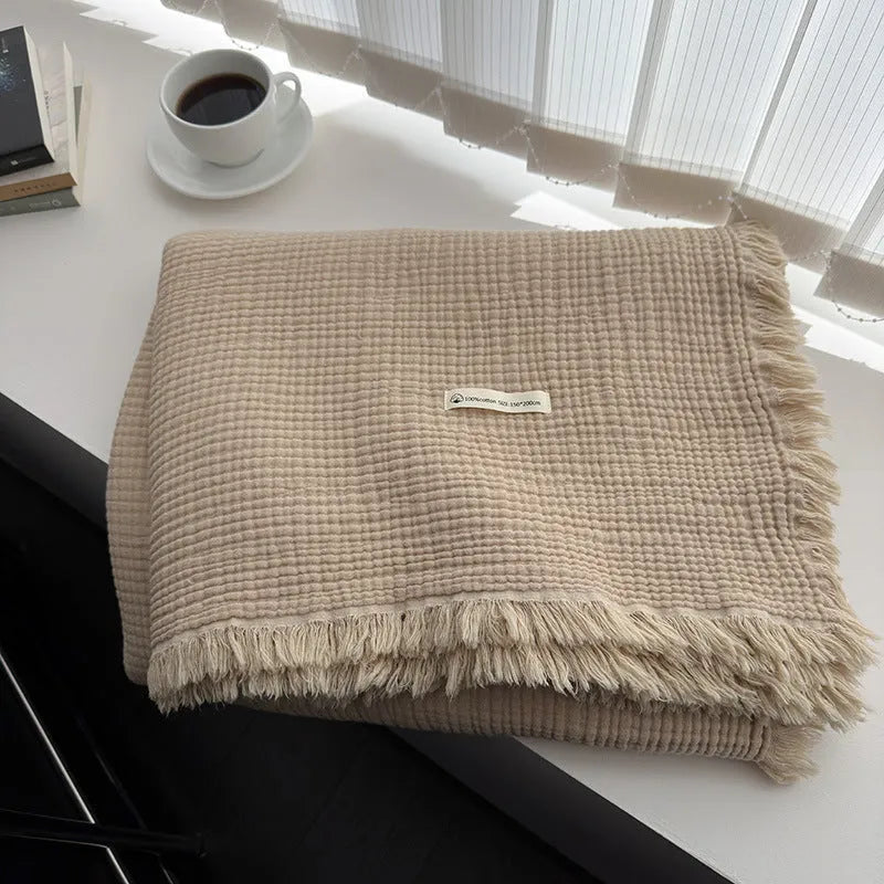 Cotton four-layer gauze blanket with tassel trim in avocado green colour, laid flat.