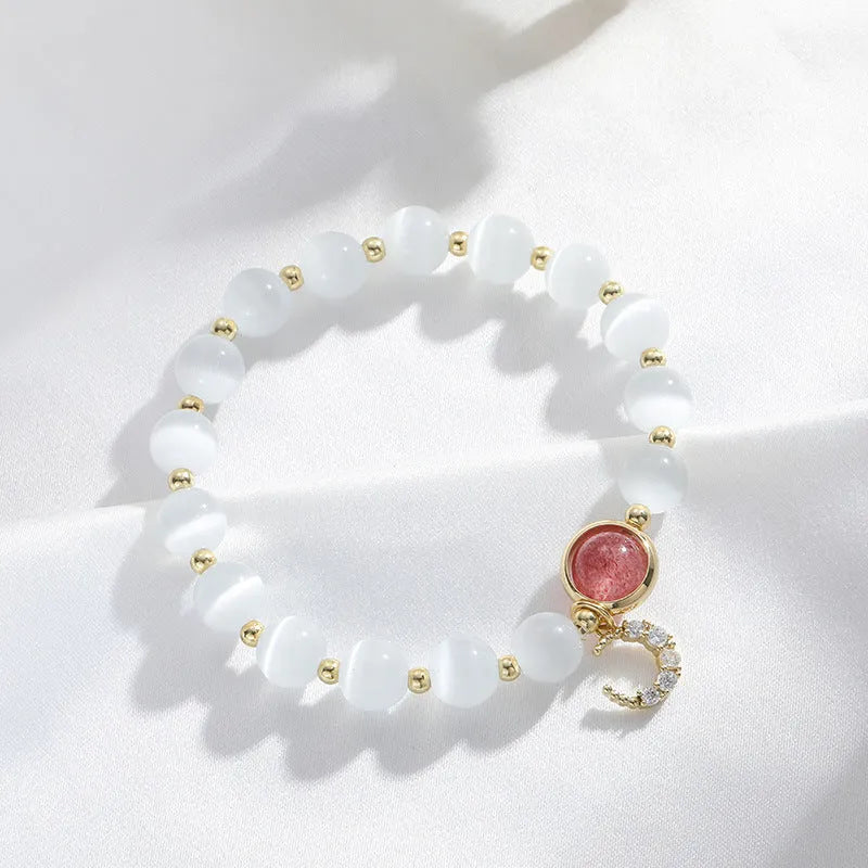 Close-up of a women's opal cat's eye stone beaded bracelet with diamond-shaped beads on a wrist.