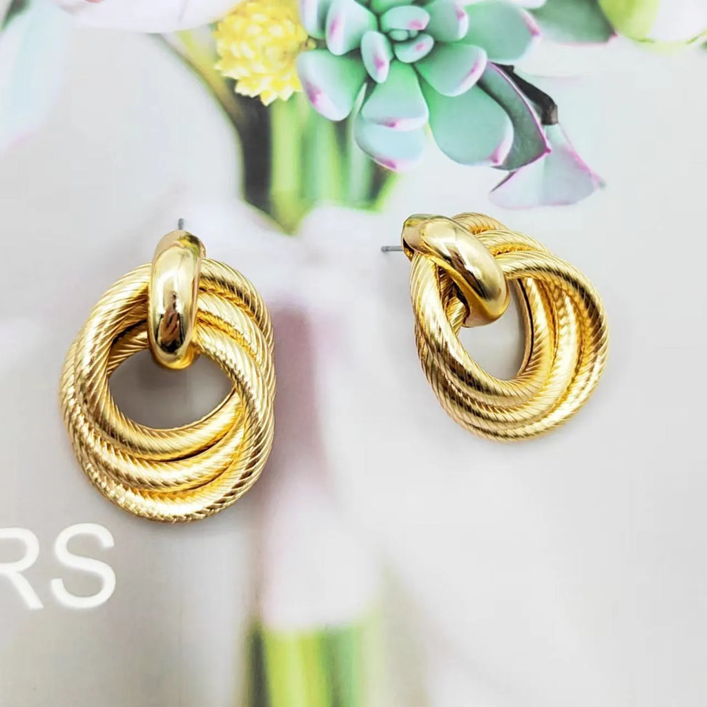 Gold geometric ring embossed twisted stud earrings on white background