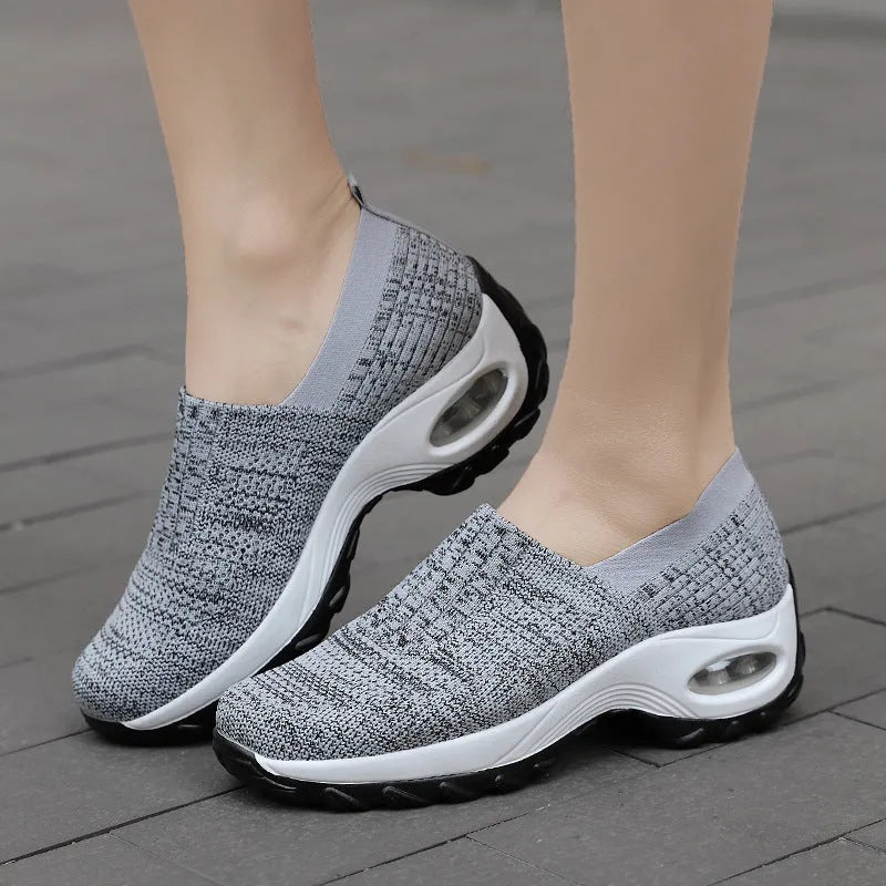 Women's mesh sports shoes in black, side view, showing breathable upper, thick bottom sole, and slip-on design