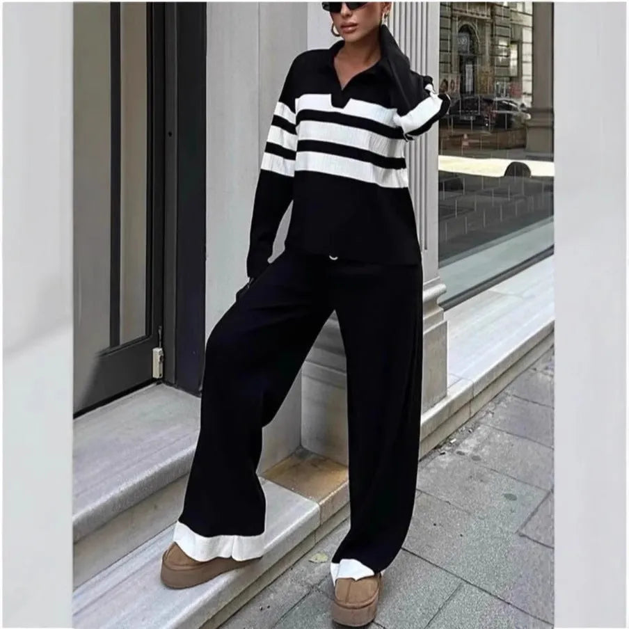 Women's black knitted polo shirt with white stripes and matching trousers laid flat.
