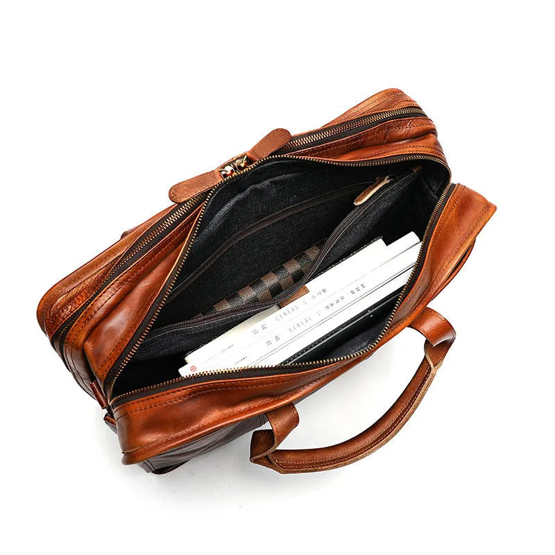 Men's vintage brown leather briefcase open to show internal laptop and camera pockets.