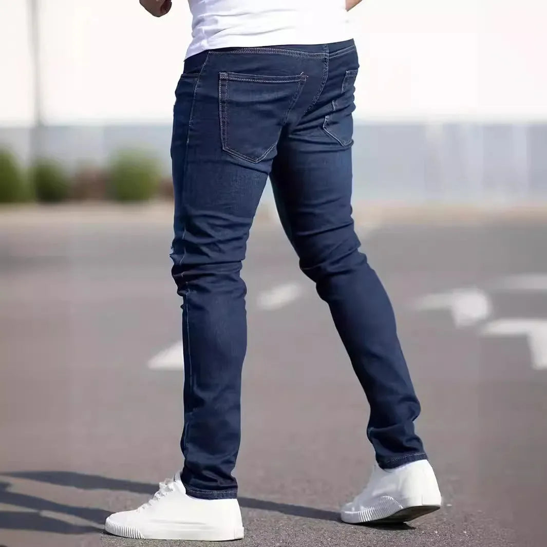 Men's dark blue slim-fit skinny jeans on a hanger, showing mid-waist and zipper fly detail.