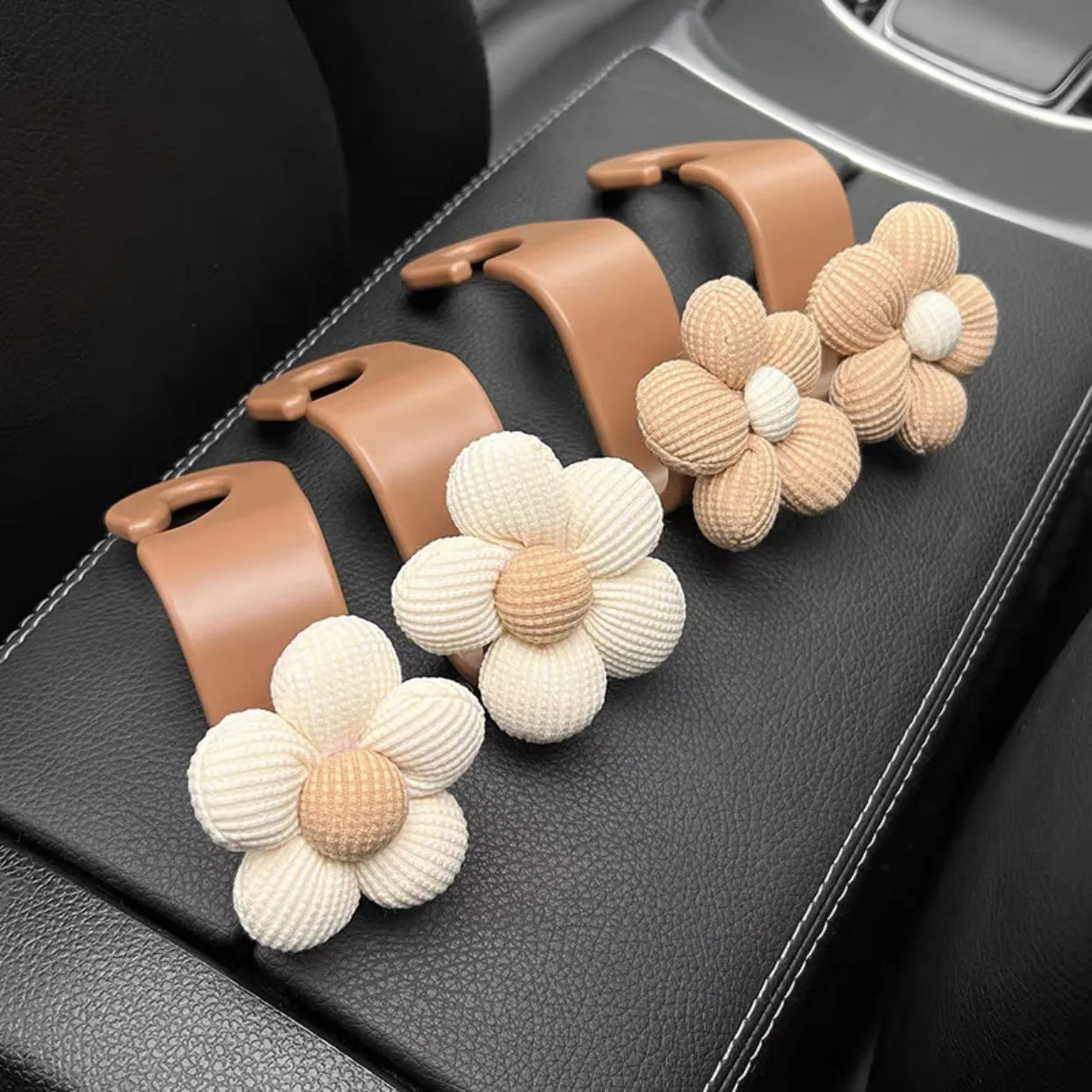 Khaki-coloured plastic car seat hook with a small decorative flower for storage.