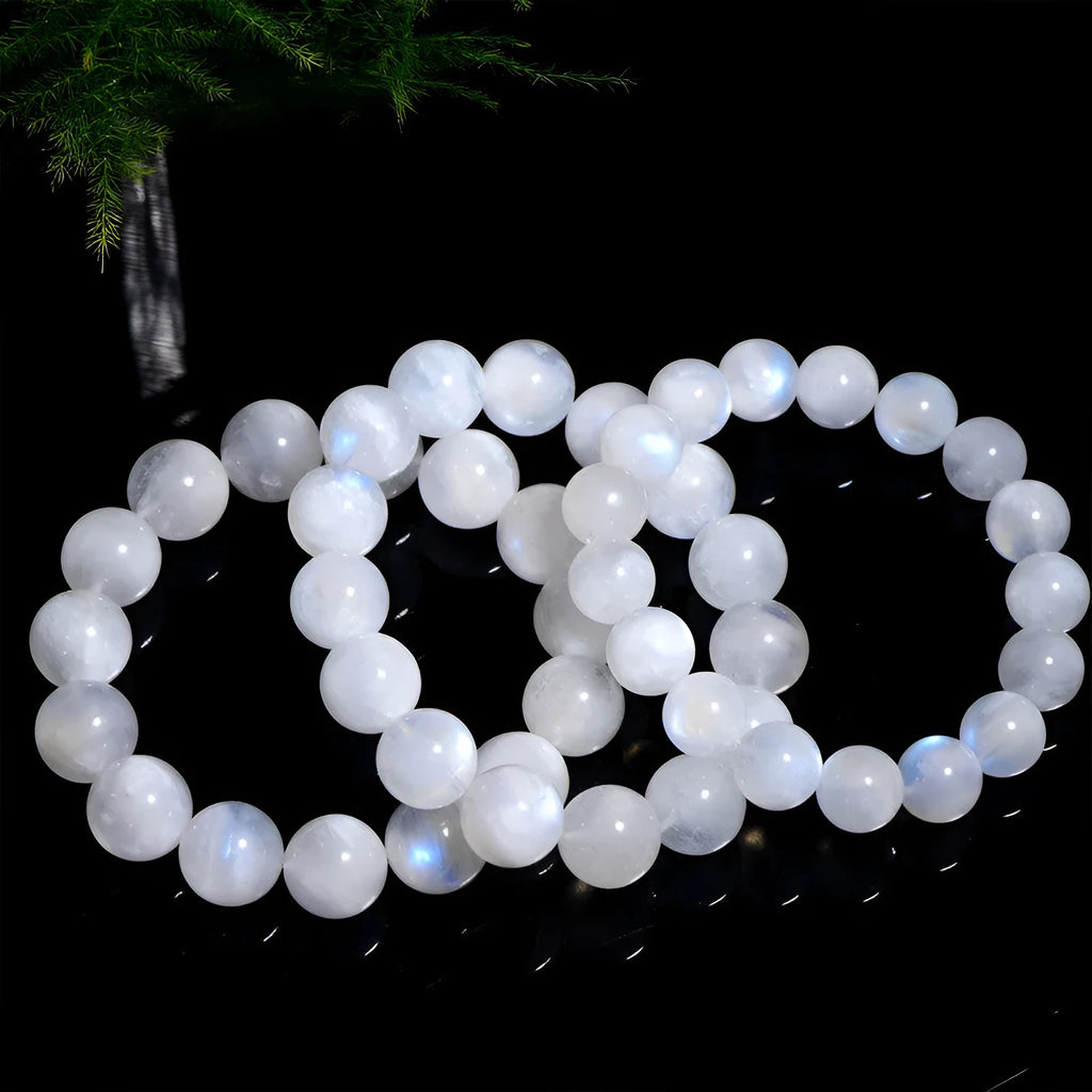 Natural blue moonlight round bead moonstone bracelet on a wrist, showing polished stones.