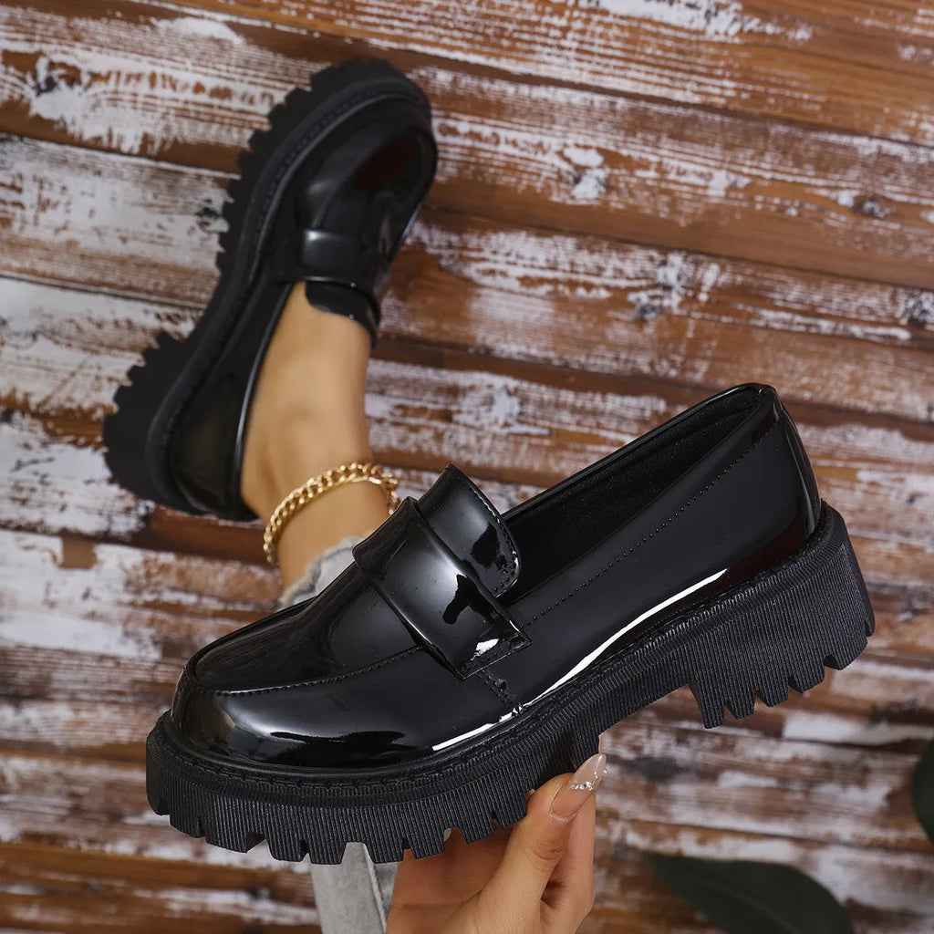 Women's black slip-on loafers with a chunky platform heel and rubber sole, shown from the side.