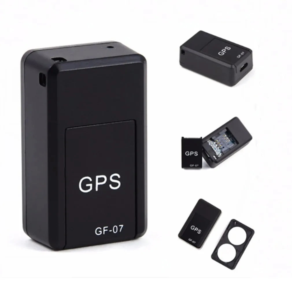 Small black magnetic GPS tracker device next to a micro-USB cable on a table.