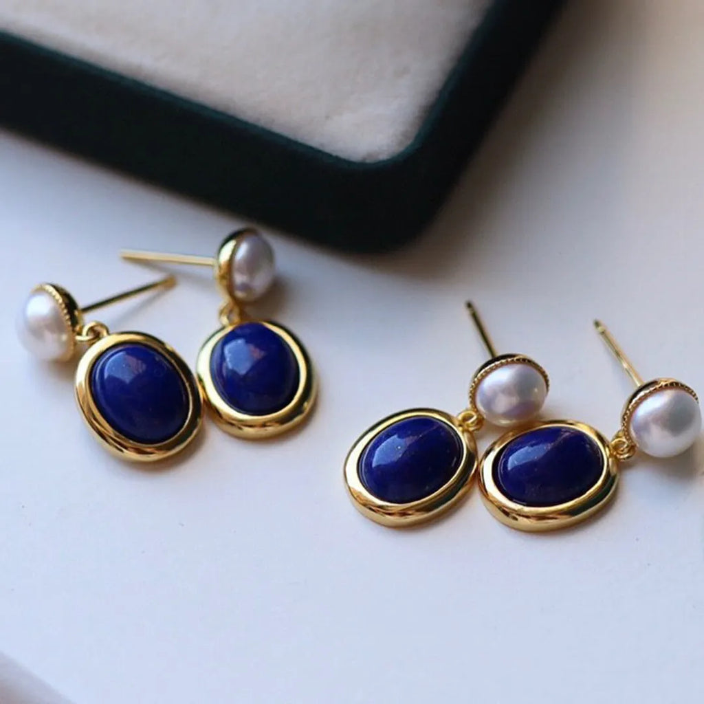 A pair of simple drop earrings featuring a blue lapis lazuli pearl set in patterned sterling silver.