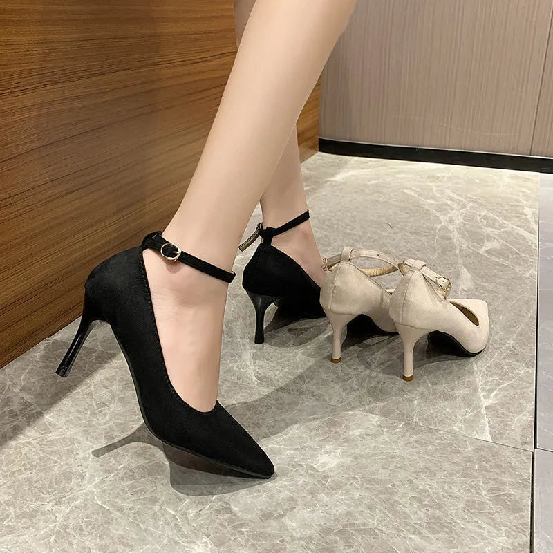 Women's black stiletto heel pump shoe with a skull pattern and buckle detail on a white background.