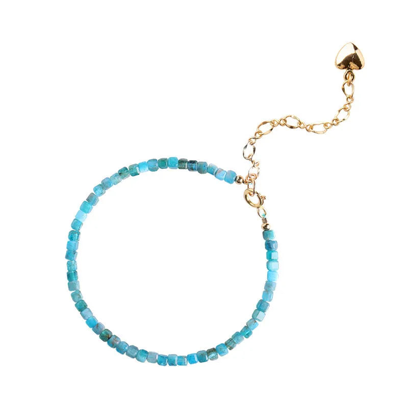 Women's blue and grey apatite crystal bracelet with diamond-cut stones on a wrist.