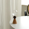 Geometric clear glass bubble vase with wooden base on tabletop with floral arrangement