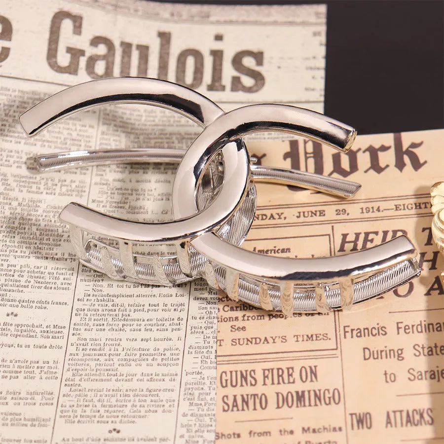 Silver metal hair claw barrette showing one of 45 designs, such as a bow or rose, on a white background.