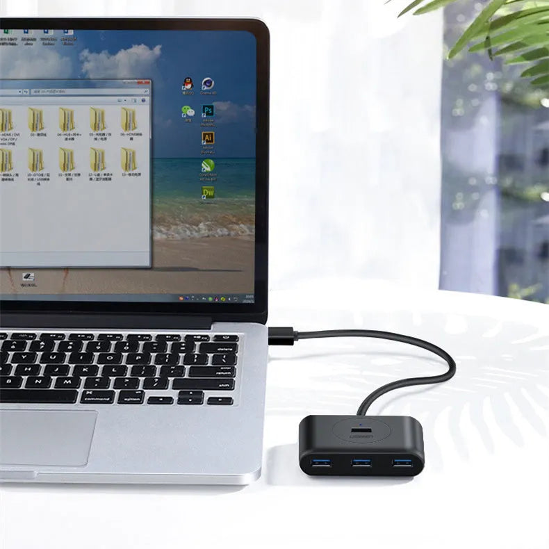 Deep black USB splitter with four ports, Micro USB power port, and indicator light on a desk